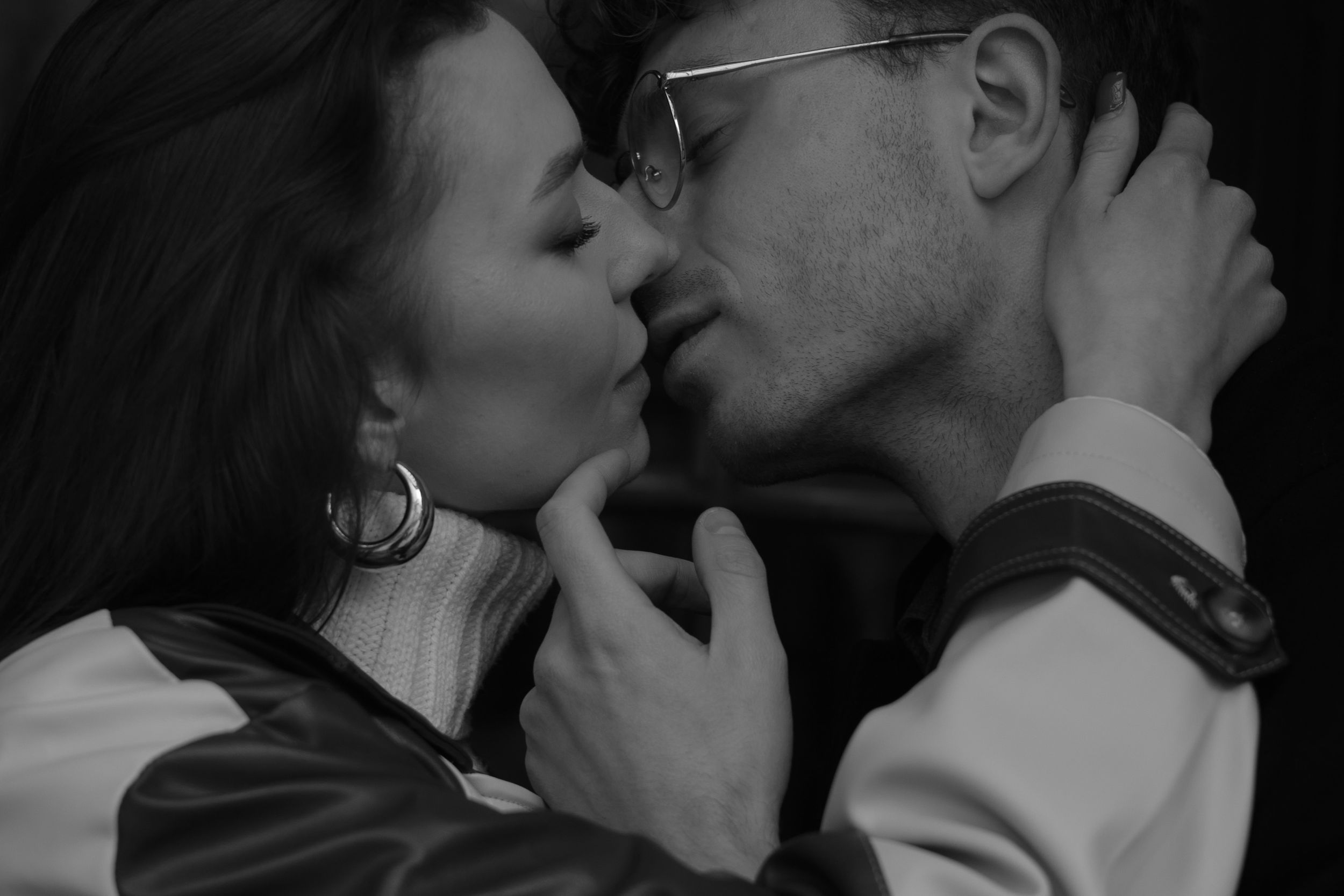 A romantic black and white photograph of a tender kiss between a couple in intimate embrace.