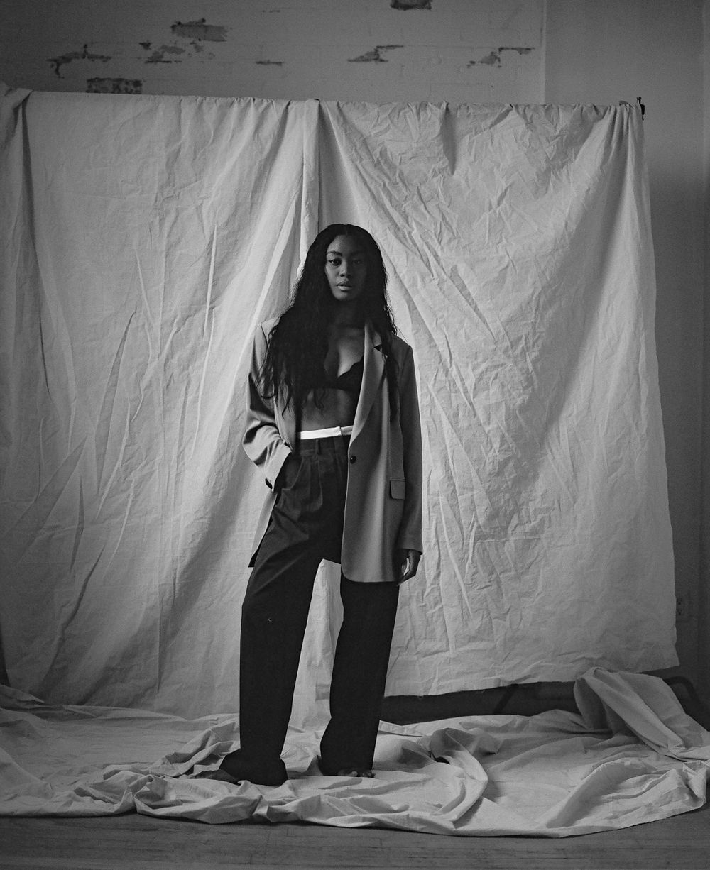 Fashion editorial portrait showing full body pose against white backdrop.