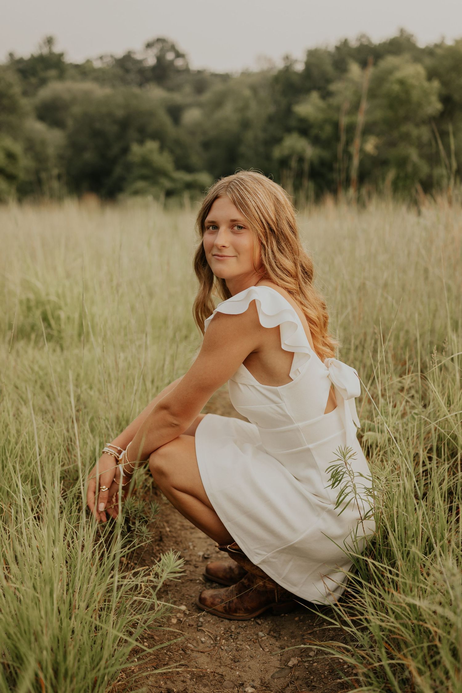 Senior poses in tall grass for summer senior photos in Lakeville MN.