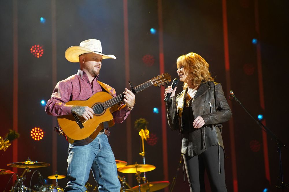 Country music performance on stage with cowboy hats and guitars.