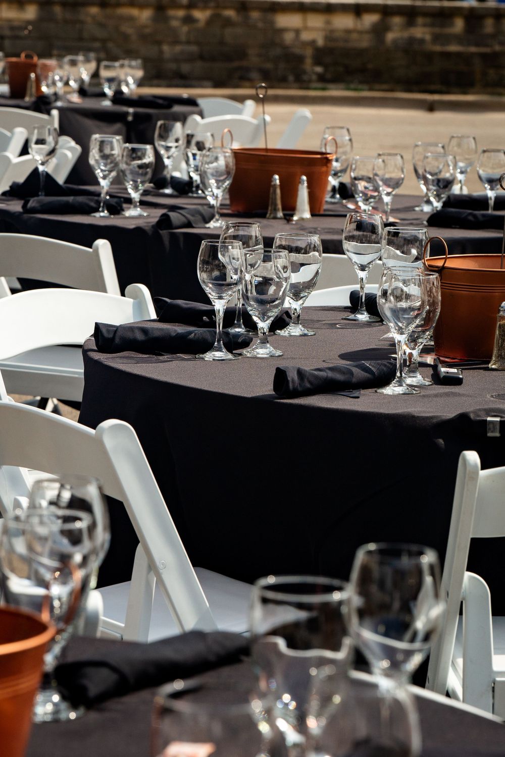Elegant table settings with wine glasses and black linens at a formal event.