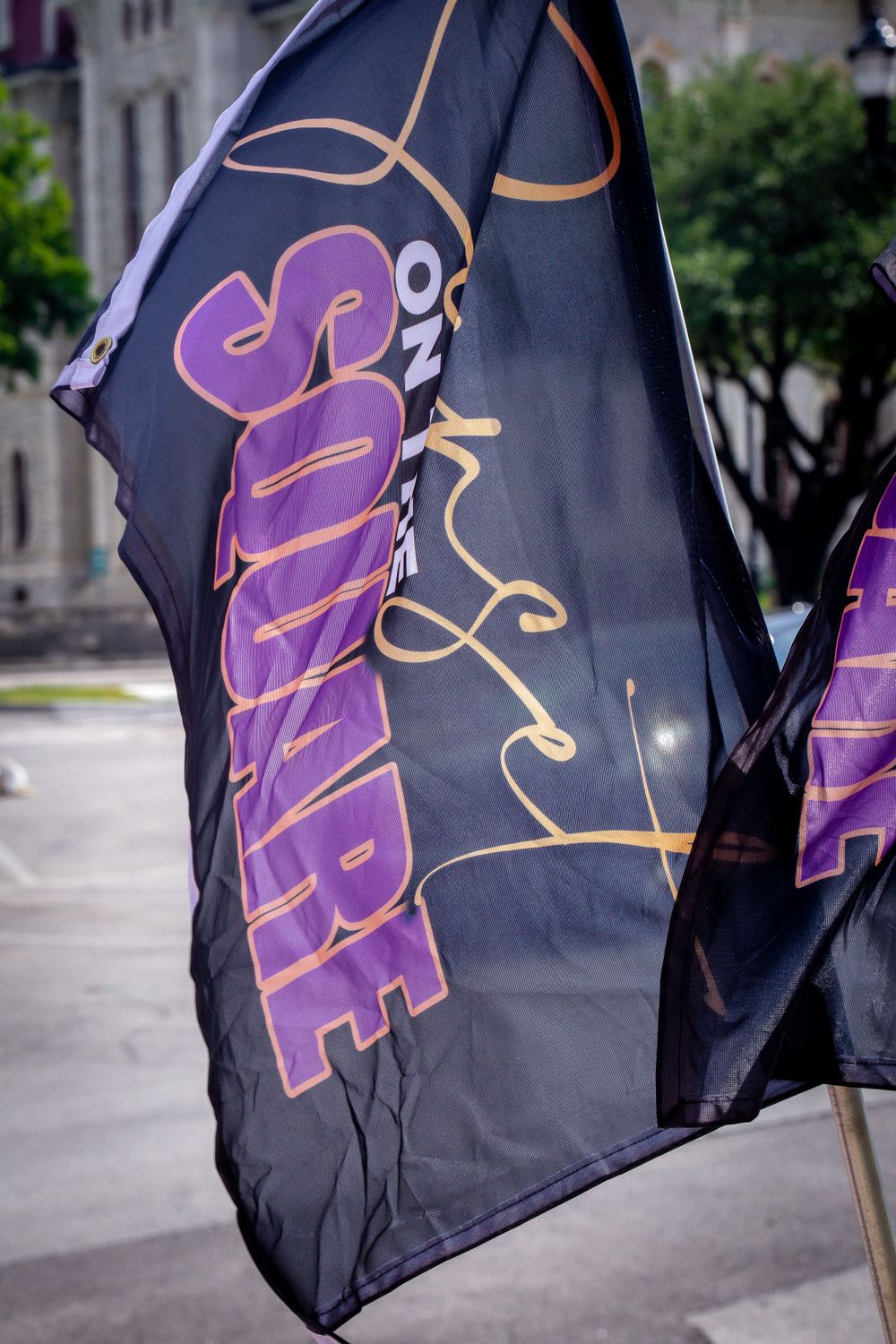 Black banner with purple and gold text fluttering in the wind.