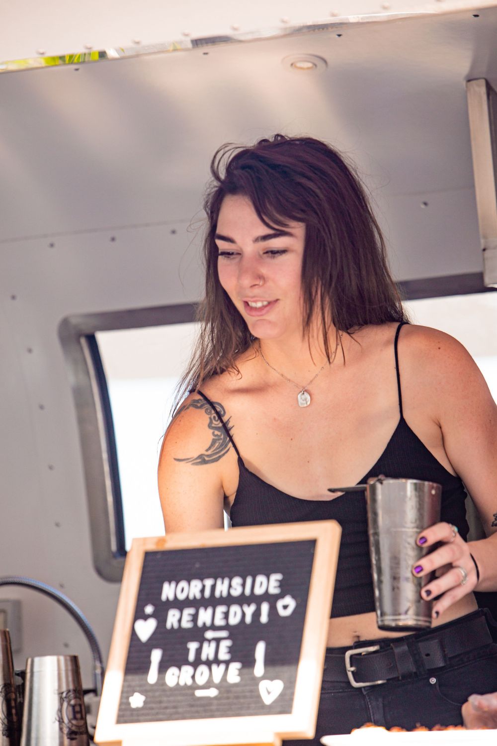 Person serving drinks from behind a counter with signage.