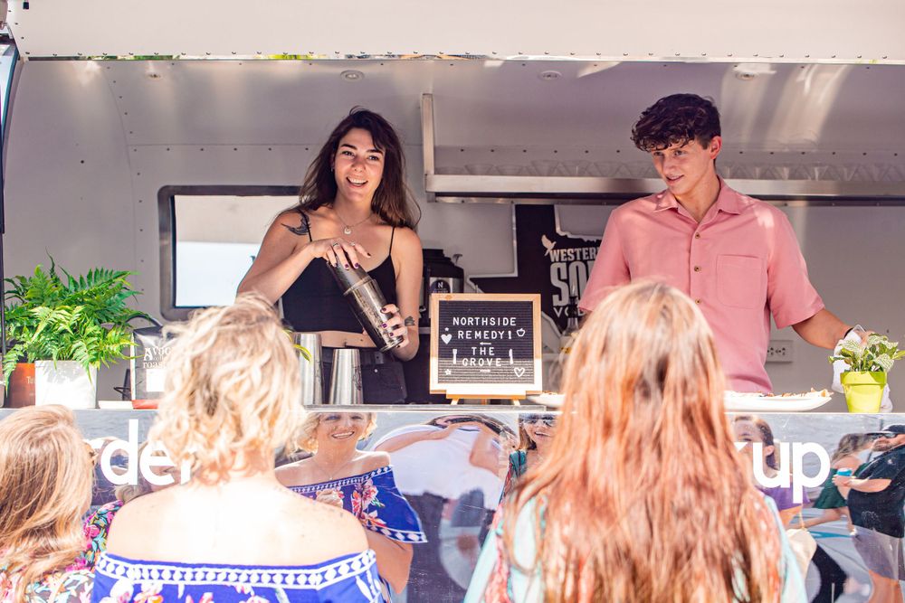 Crowd mingling at an outdoor food and beverage service counter.