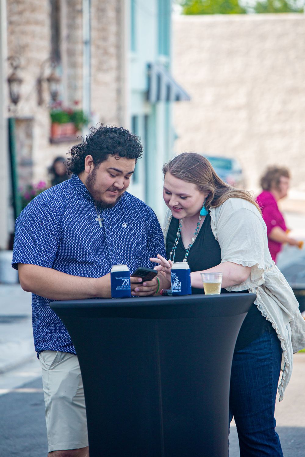 Two people sitting at a table sharing a meal and looking at their phones.