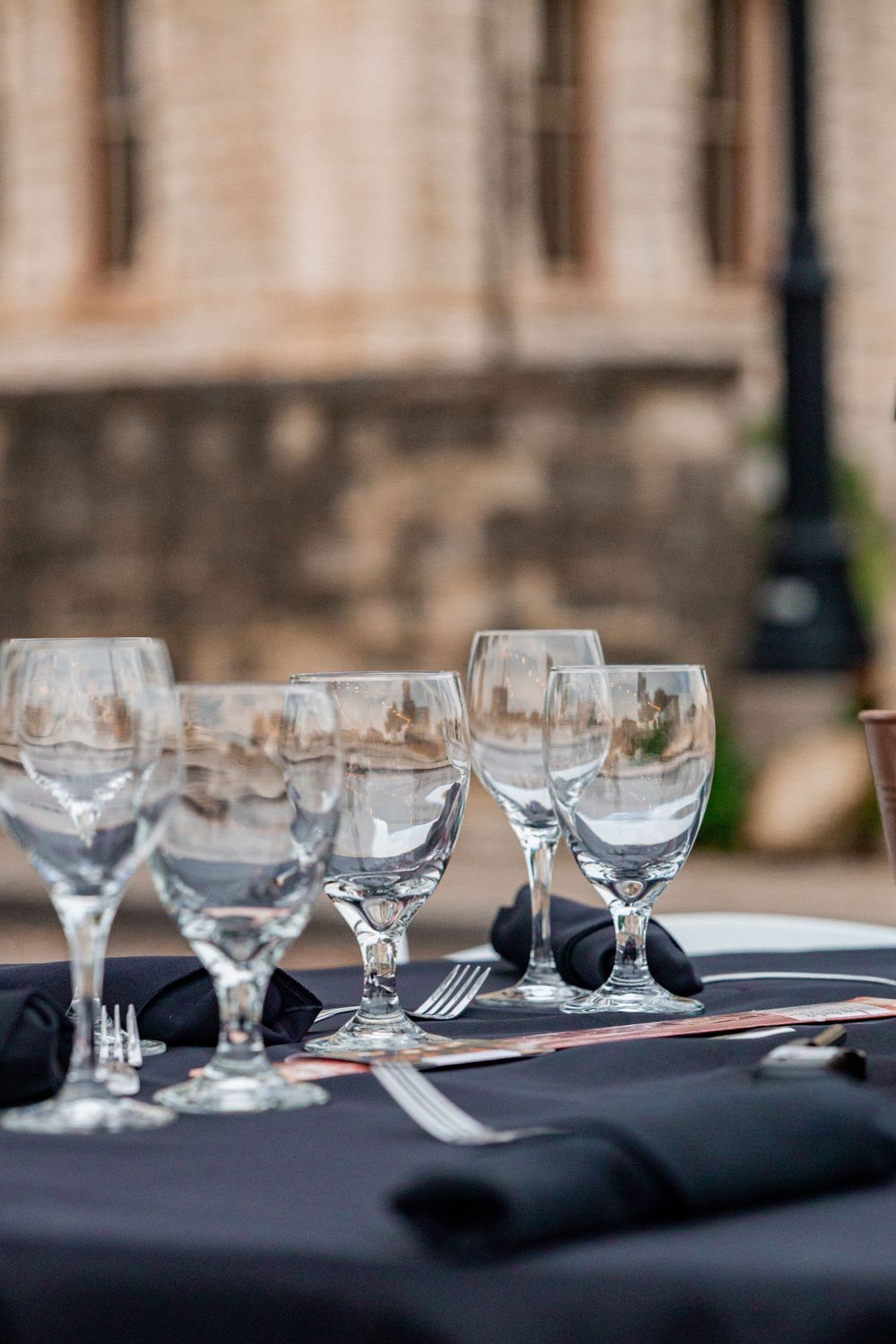 Row of elegant wine glasses set up on black tablecloth at formal event.