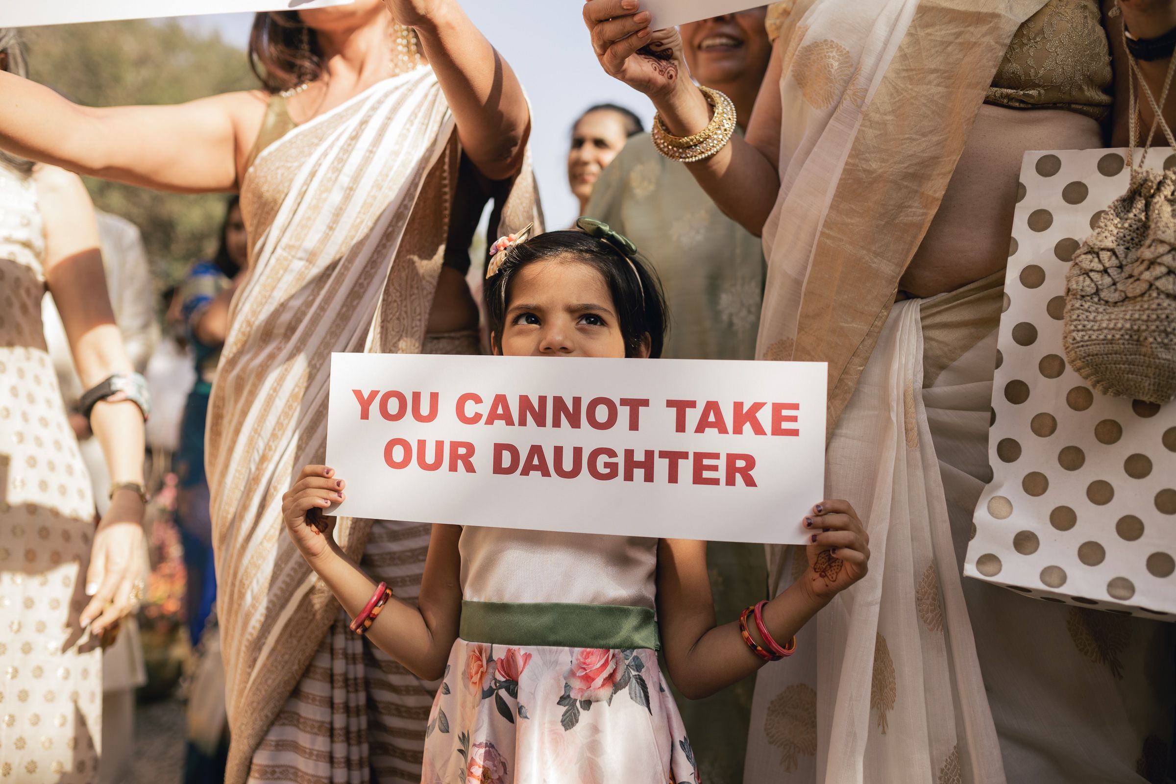 Person holds protest sign reading 'You Cannot Take Our Daughter' during public demonstration.