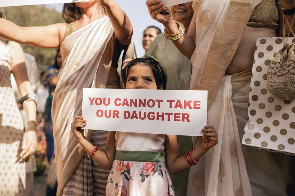Person holds protest sign reading 'You Cannot Take Our Daughter' during public demonstration.