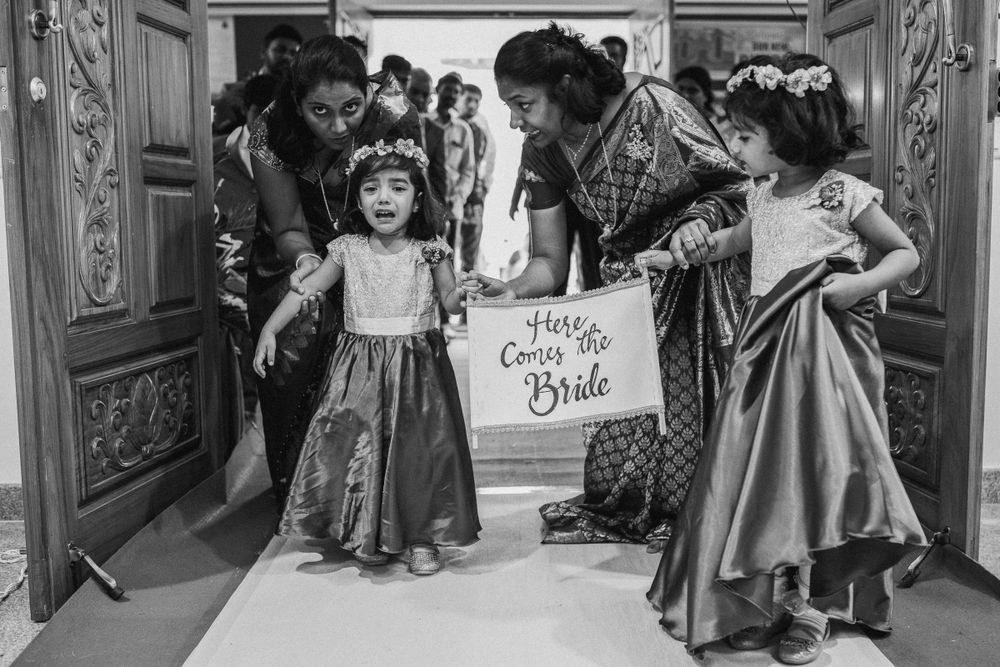 Vintage black and white photograph showing people gathered in a church doorway holding a 'Here Comes the Bride' sign.