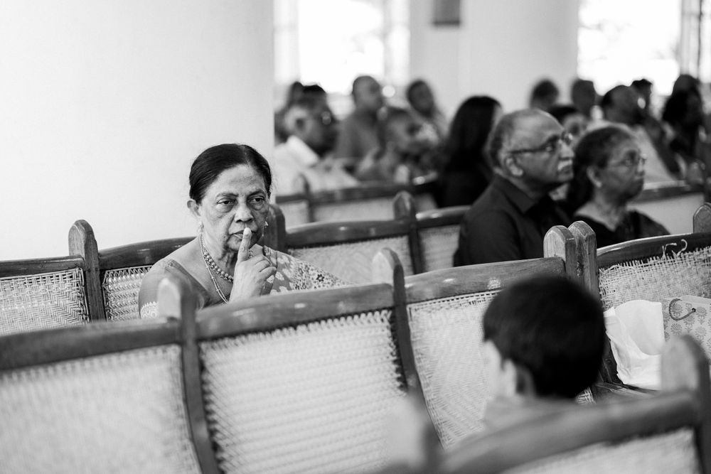 Black and white photo of people seated in rows of wooden pews inside a church or meeting hall.