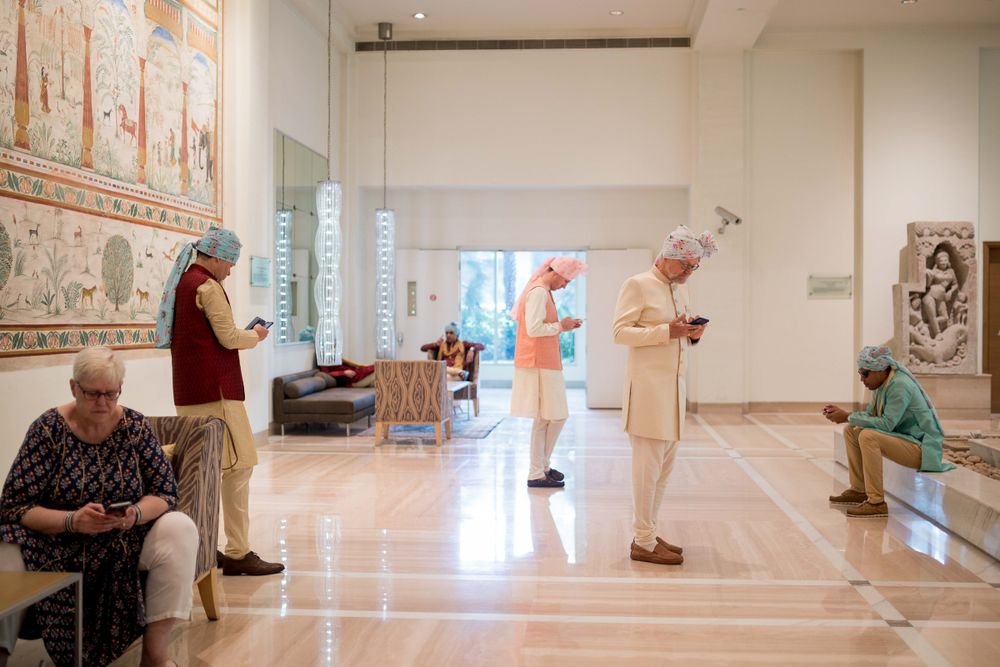 People in a bright indoor hallway with decorative wall art and polished floors at a healthcare or senior living facility.