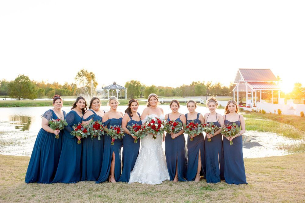 Wedding party in navy and white attire posing together at sunset.