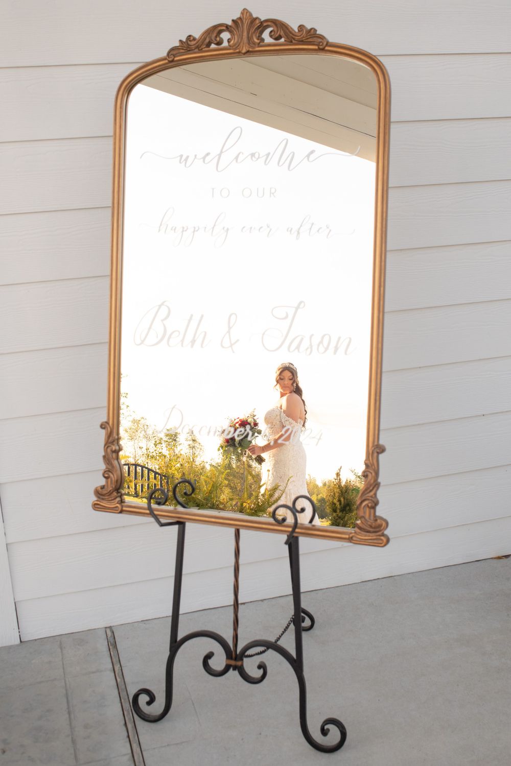 Ornate gold-framed mirrors displayed against white wooden wall for wedding decor.