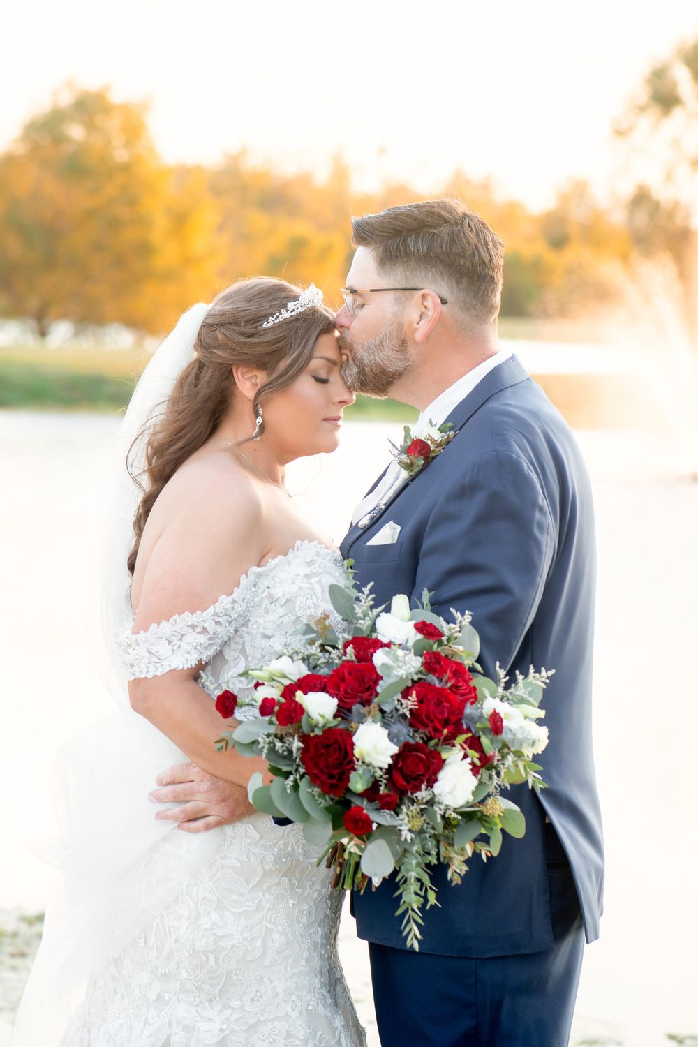 Romantic sunset wedding portrait with a stunning red and white bouquet.