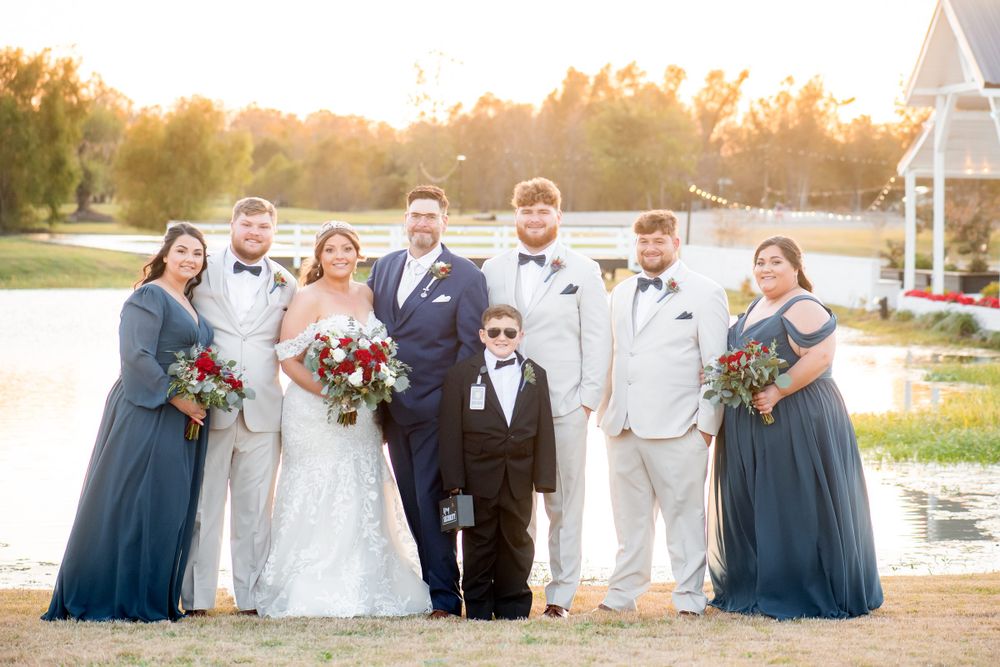 Wedding party in navy blue and white attire gathered for a group photo.