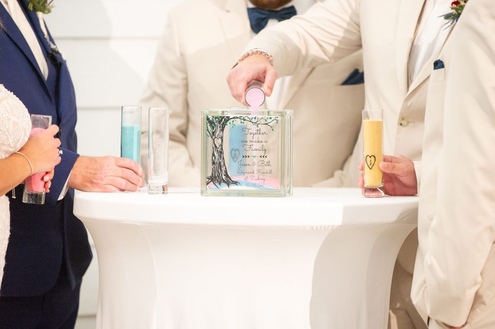Wedding party members sign official documents at a white table during ceremony.