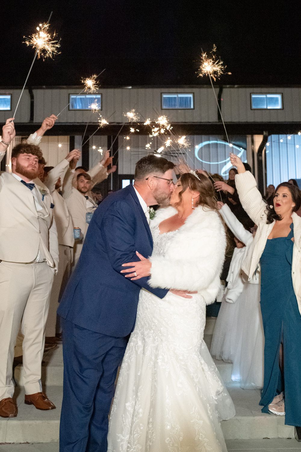 Wedding party celebrates with sparklers during an evening reception.