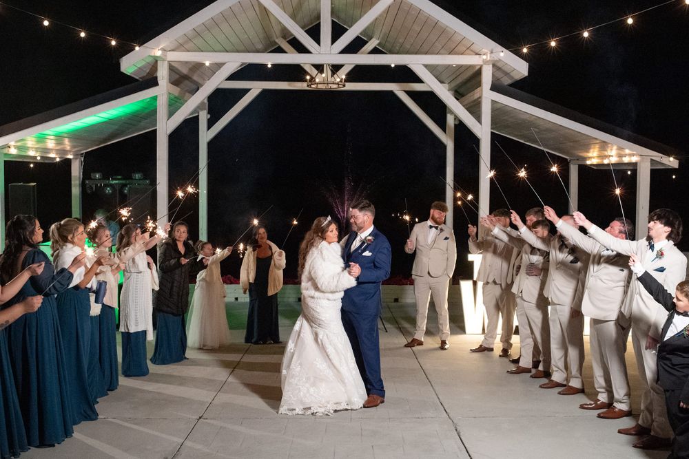 Evening reception celebration with string lights and guests dancing under wooden beams.