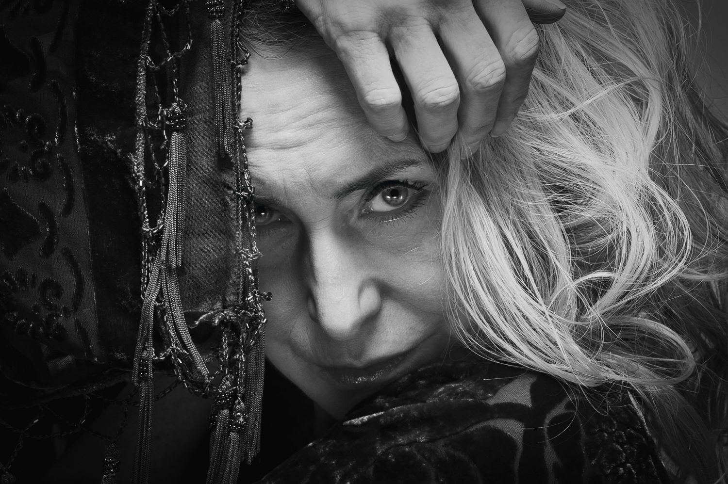 Black and white artistic portrait with dramatic lighting and wind-swept blonde hair.