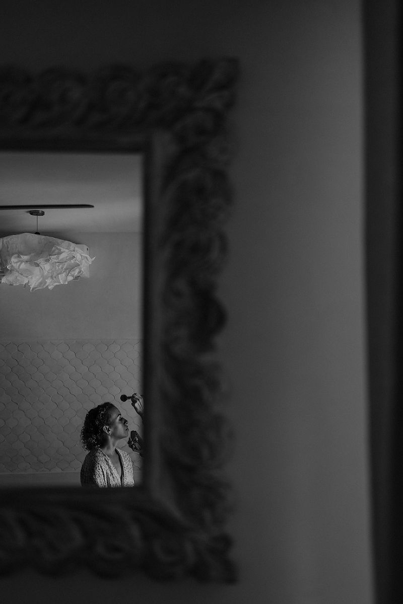 Black and white mirror reflection of a bride getting ready, captured in an ornate vintage frame.