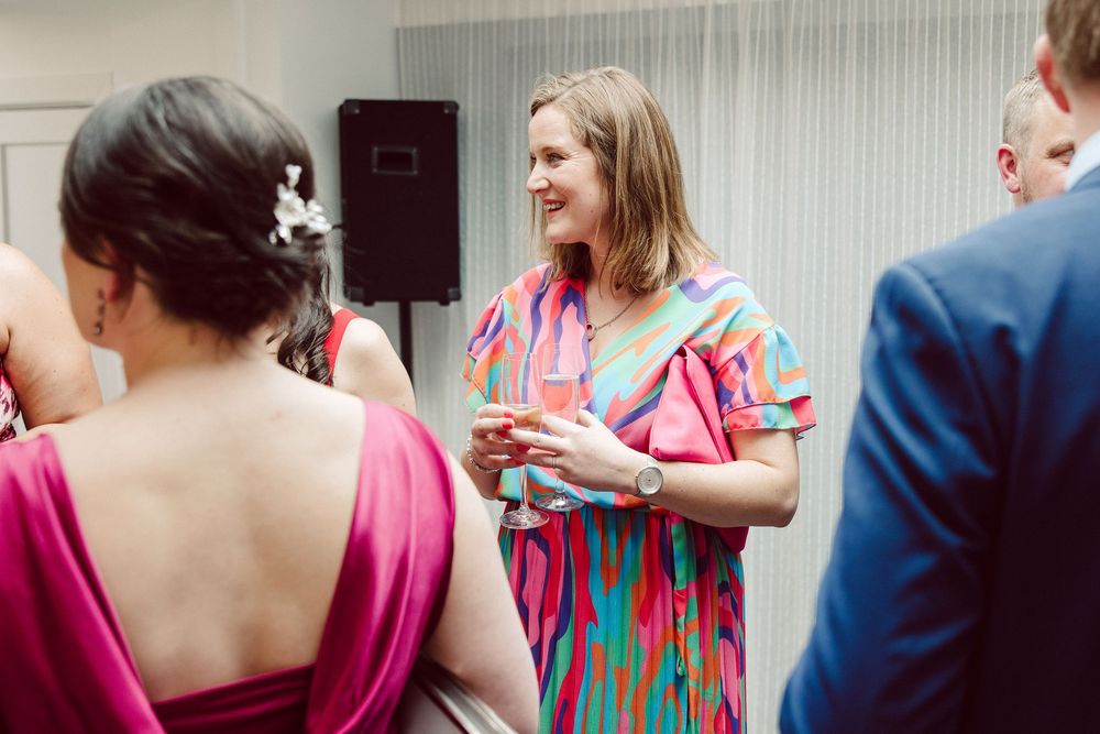 People in pink and blue attire gather together in what appears to be an indoor social event or celebration.