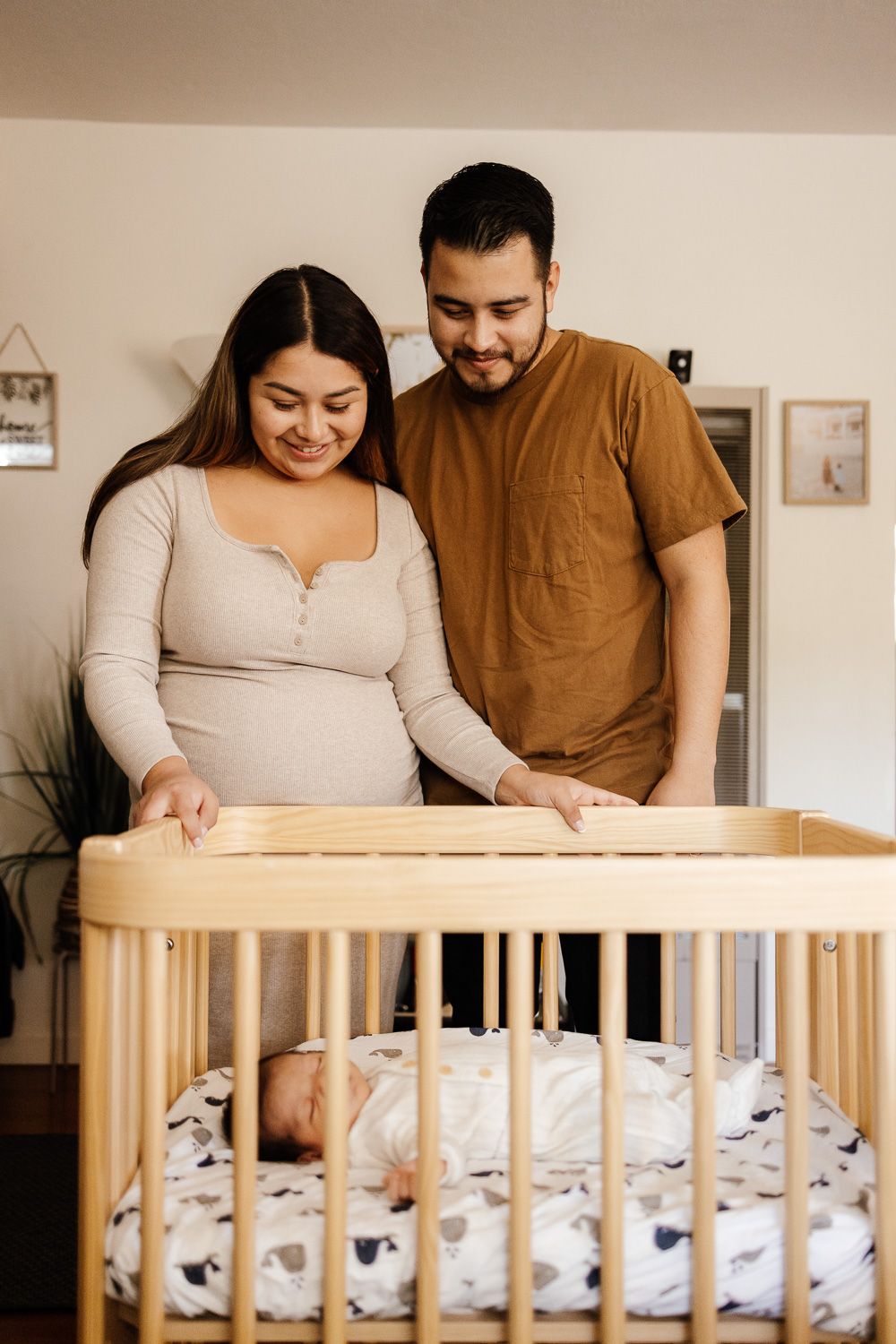 Parents look lovingly at their sleeping baby in crib