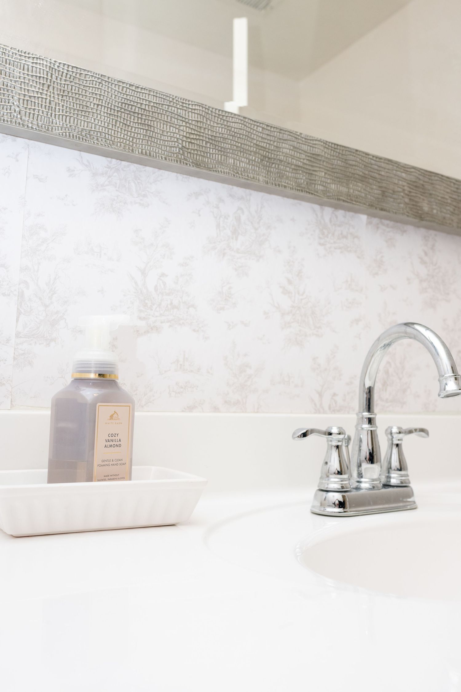 Elegant bathroom vanity with chrome faucet and textured wallpaper detail.