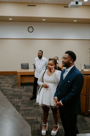Two people share a lighthearted conversation in an office setting with fluorescent lighting.