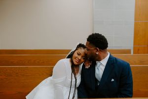 A joyful couple shares an intimate moment while sitting in a wooden church pew.