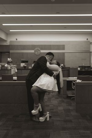A black and white photo shows a couple sharing a romantic dance in a courthouse.