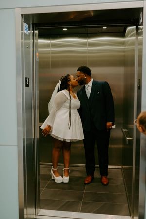 A couple shares a romantic moment in an elevator on their wedding day.