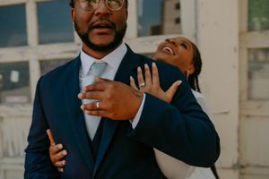 A couple shares a playful embrace while wearing formal wedding attire.