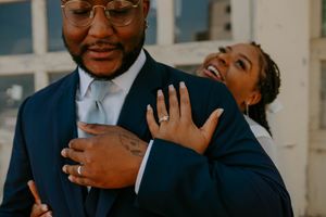 A couple shares a candid moment of laughter and joy in formal attire.