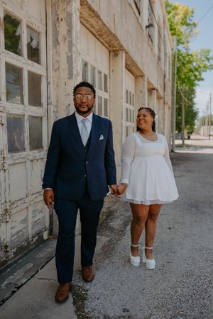 A couple walks together along a sunlit building corridor.
