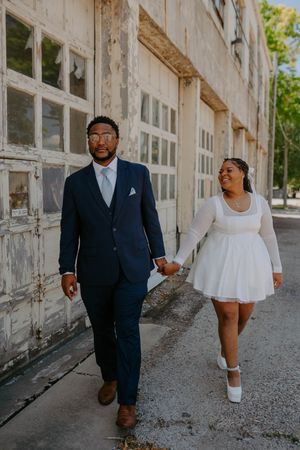 A couple strolls together on a bright sunny day along an architectural walkway.