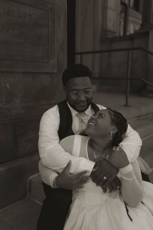 A couple shares a romantic moment outside a historic building entrance.