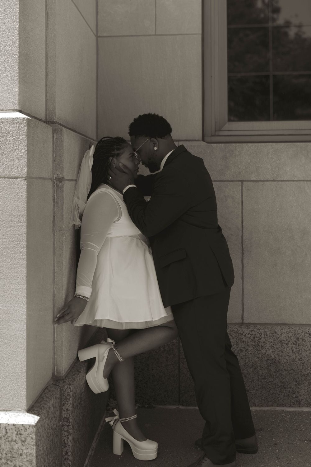 A romantic black and white sequence showing a couple embracing near a building wall.