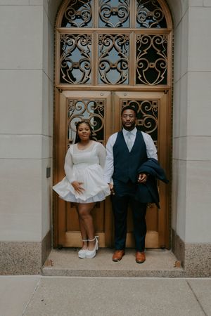 Playful family portraits taken in the doorway of a historic building with ornate architecture.