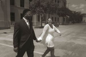 A couple walks together outdoors in formal black and white attire.