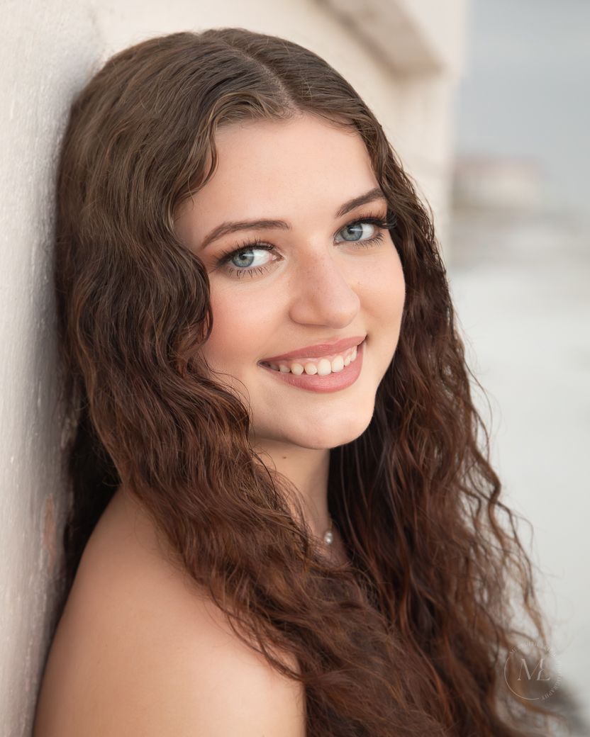 Portrait series showing a natural beauty with long brown curls against a soft blurred background.