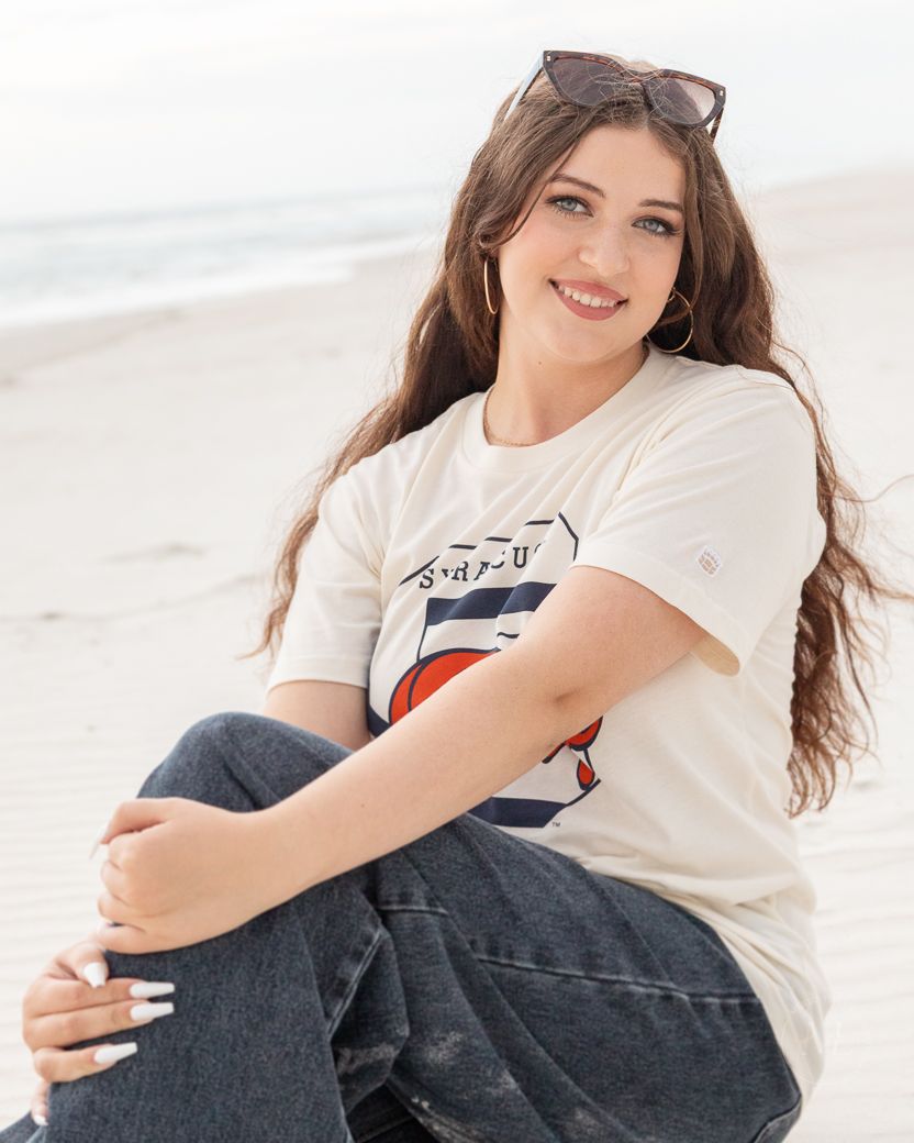 Casual portraits of person wearing white t-shirt and jeans while sitting and smiling.