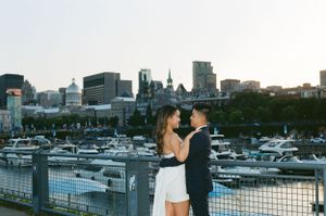 Couple embracing with cityscape and marina view at sunset.