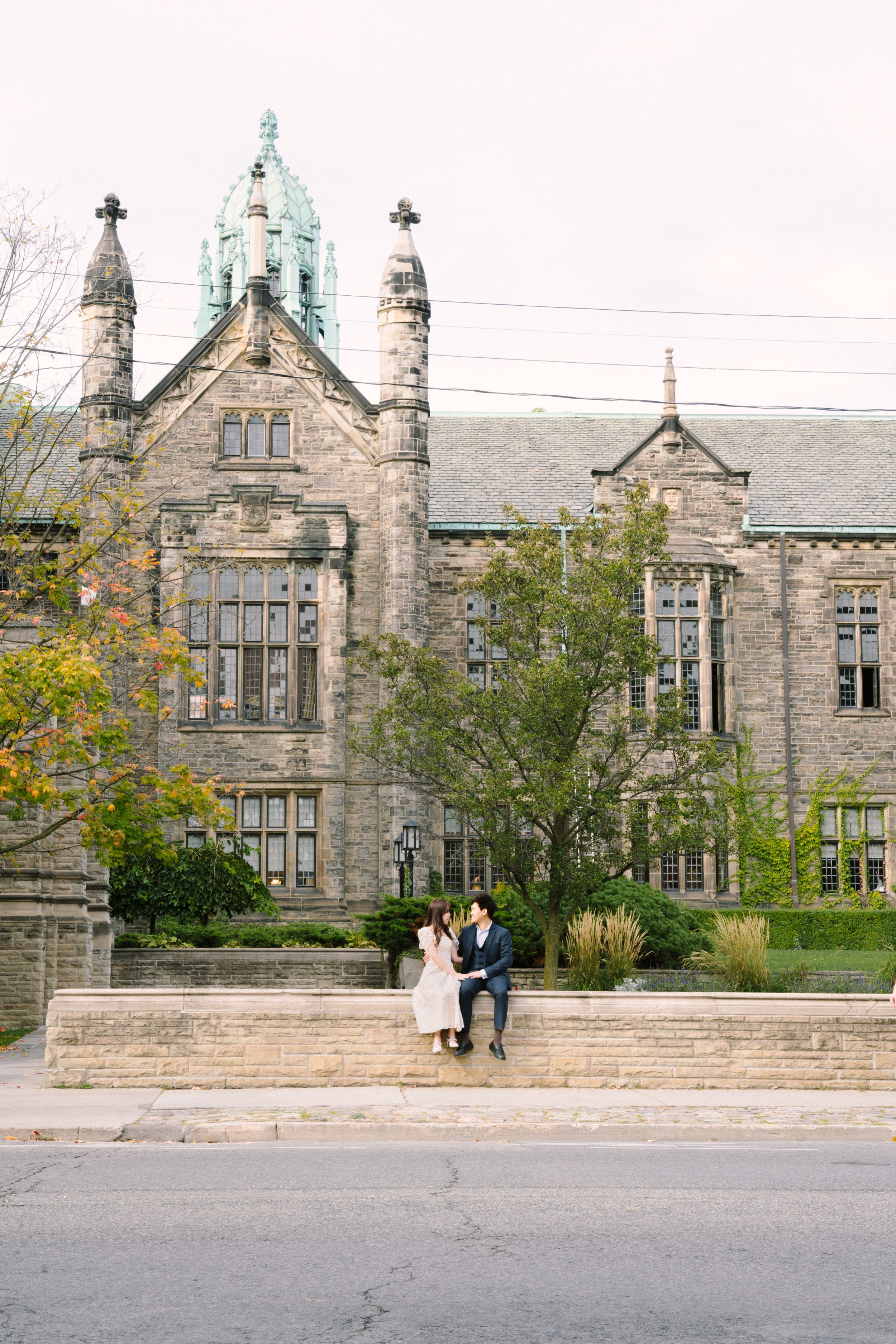 Couple sitting on steps in front of historic gothic university building.