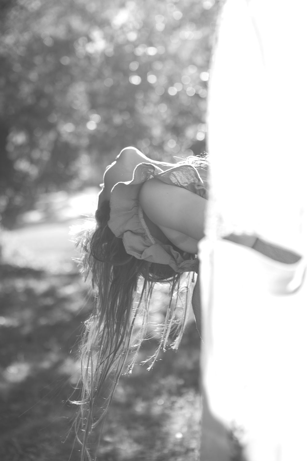 Black and white artistic photo showing hair movement and shadow silhouettes against a bright background.