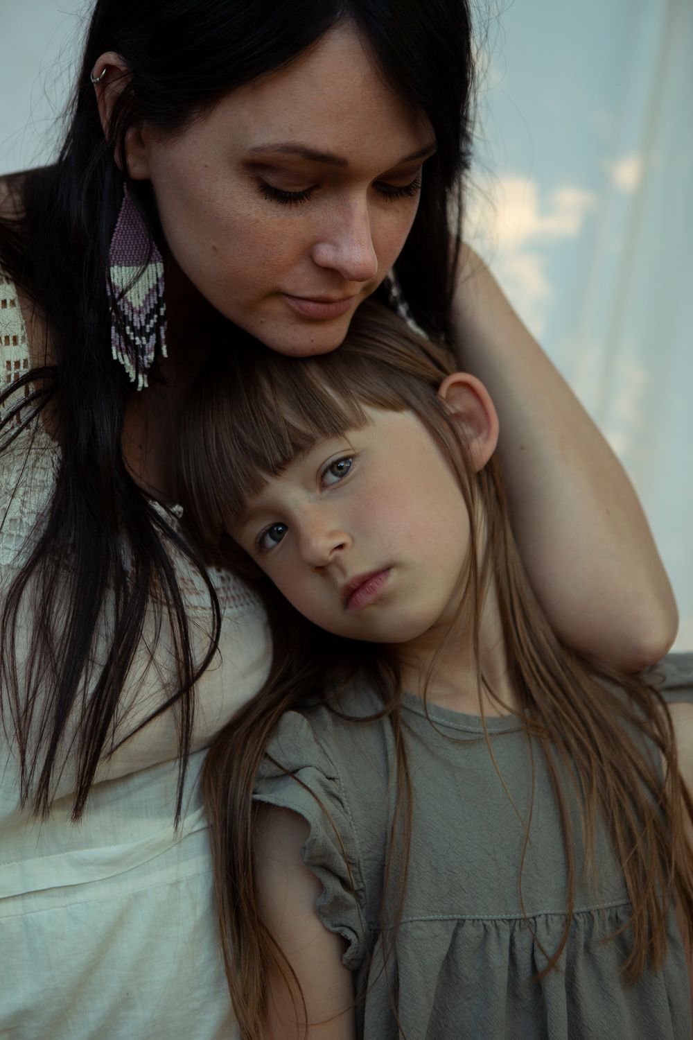 A tender moment captured between parent and child in soft lighting with decorative earrings visible.