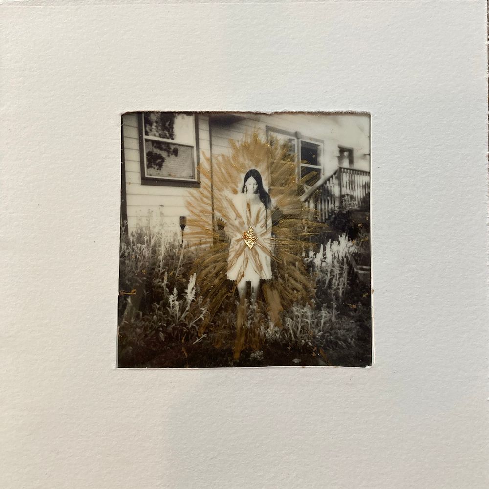 Vintage sepia-toned polaroid photograph showing a figure in a light coat standing in front of a house exterior.