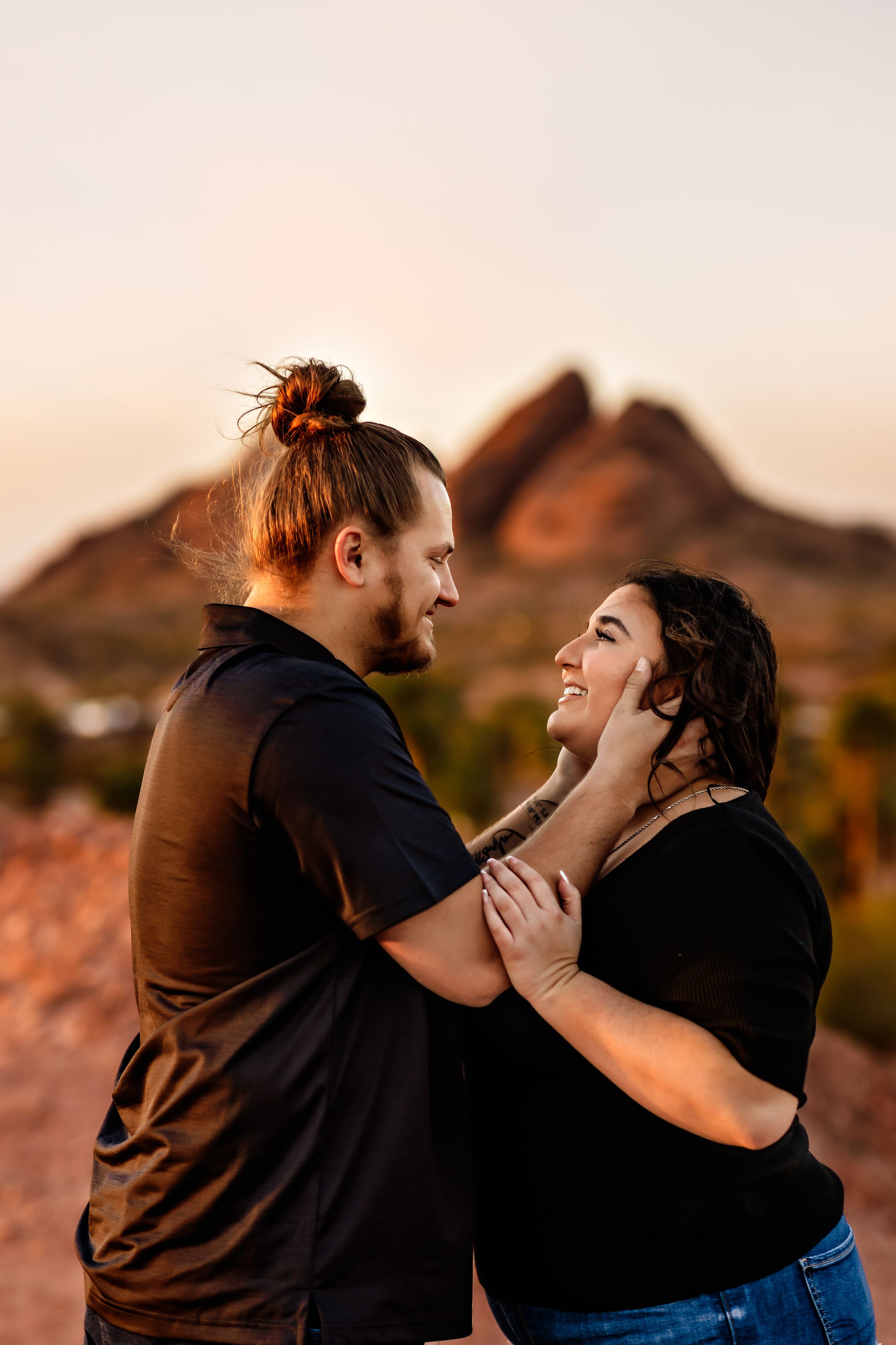 A loving couple shares an intimate moment during golden hour at a scenic desert mountain location.
