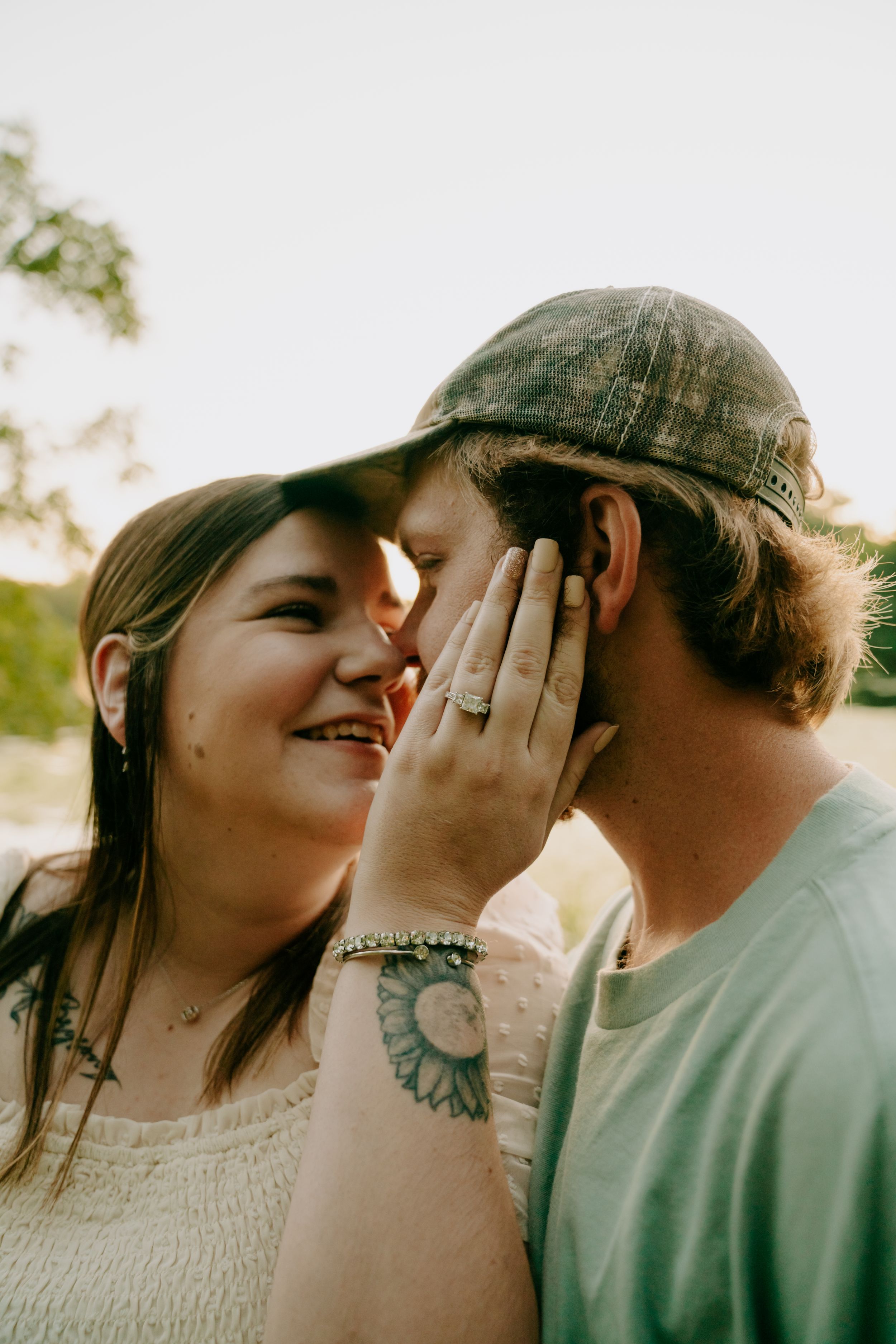A couple shares a tender moment outdoors with genuine smiles.
