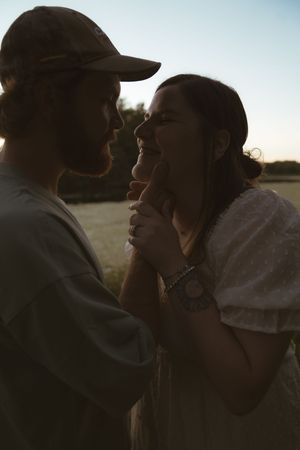 Silhouetted couple sharing tender moments against a bright sky backdrop.