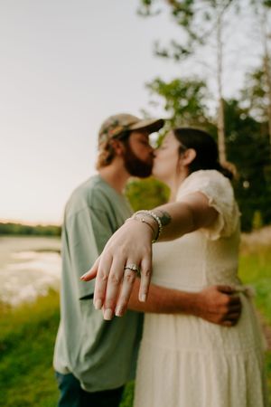 Romantic embrace captured in golden sunlight with an engagement ring prominently displayed.